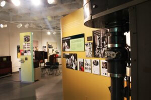 View of the museum, with an electron microscope in the foreground, and artifacts and photos visible in the background.